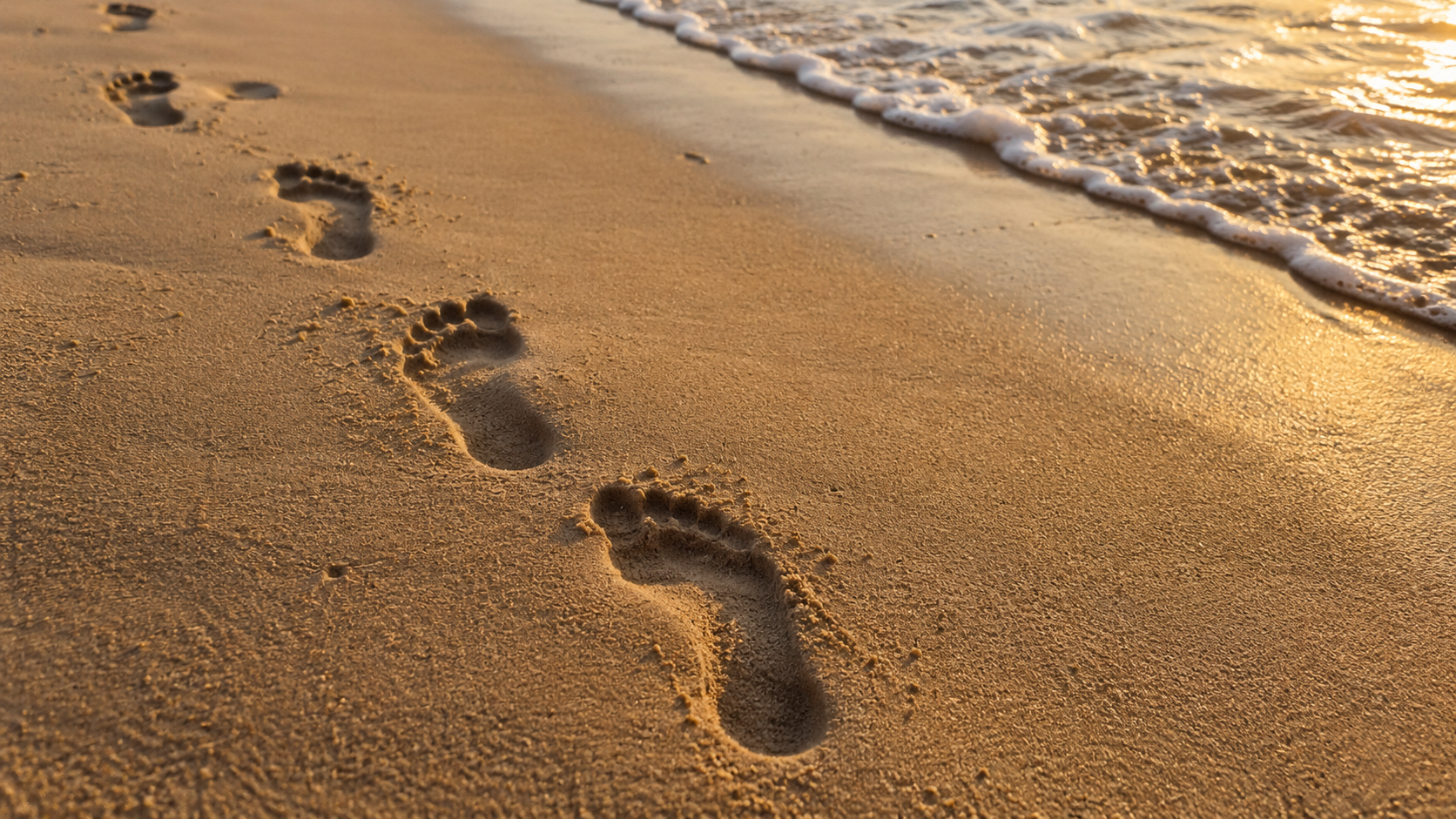 Photo de traces de pas sur du sable ou de la neige, cadrage graphique, lumière rasante